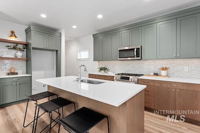 Kitchen with light wood finished floors, stainless steel appliances, decorative backsplash, light countertops, and recessed lighting