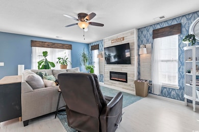 Living room featuring ceiling fan, a large firepla