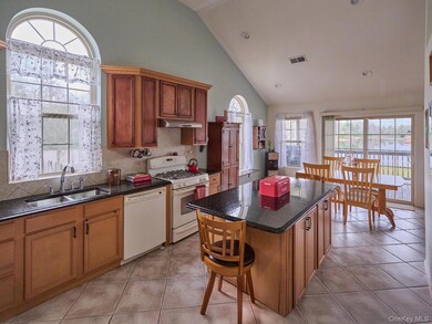 Kitchen with decorative backsplash, white appliances, a kitchen island, light tile patterned floors, and high vaulted ceiling