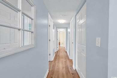 Corridor featuring light wood finished floors, a t