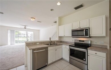 Kitchen with stainless steel appliances, open floor plan, white cabinetry, and light tile patterned floors