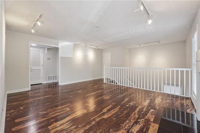 Spare room featuring track lighting and dark wood-style floors