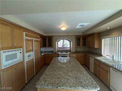 Kitchen with built in appliances, a center island, glass insert cabinets, light stone counters, and recessed lighting