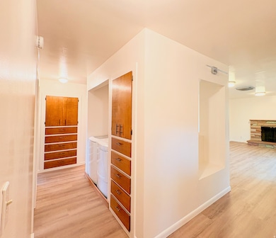 Corridor featuring light wood-type flooring, separate washer and dryer, and stairway