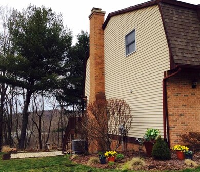 Side view of home with landscaped beds and tree li