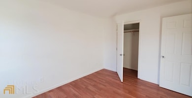 Unfurnished bedroom featuring wood finished floors, baseboards, and a closet