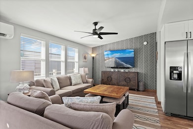 Living room featuring an AC wall unit, ceiling fan