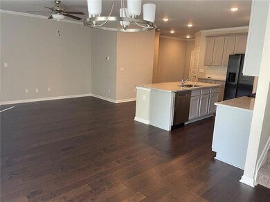 Kitchen featuring black refrigerator with ice dispenser, sink, stainless steel dishwasher, and dark wood-type flooring