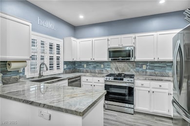 Kitchen with white cabinets, stainless steel appliances, tiled backsplash, a peninsula, and quartz counters w/recessed lighting