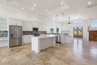 Kitchen featuring a raised ceiling, white cabinets, a ceiling fan, backsplash, and a kitchen island