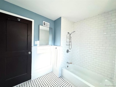 Bathroom featuring shower / washtub combination and wainscoting