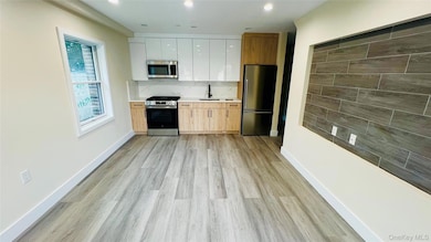 Kitchen with appliances with stainless steel finishes, light wood-style flooring, decorative backsplash, white cabinets, and modern cabinets