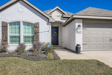 View of front of home with brick siding, a garage, roof with shingles, and a front lawn