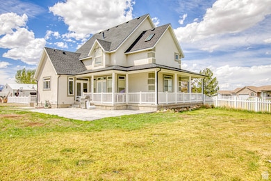 Rear view of property featuring a yard, a shingled roof, stucco siding, and fence