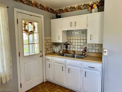 Kitchen featuring countertops light, white cabinets, dark parquet flooring, and washbasin