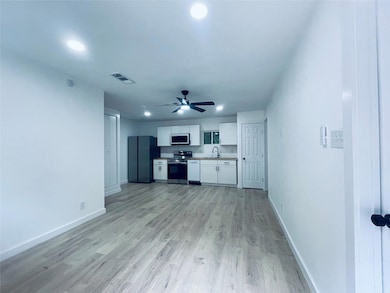 Kitchen featuring white cabinetry, stainless steel appliances, light wood-style floors, recessed lighting, and light countertops
