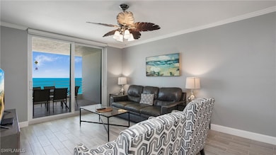 Living area with crown molding, wood finish floors, a water view, a ceiling fan, and expansive windows