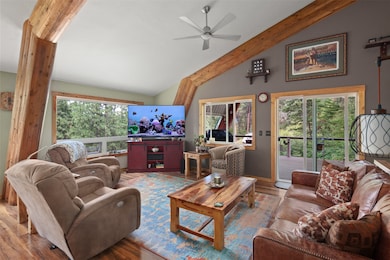 Living room featuring healthy amount of natural light, wood finished floors, a ceiling fan, beam ceiling, and high vaulted ceiling