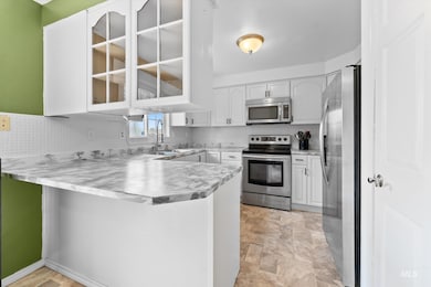 Kitchen with stainless steel appliances, white cabinets, a peninsula, and decorative backsplash