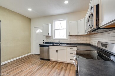 Kitchen with light wood-type flooring, white cabinetry, tasteful backsplash, sink, and stainless steel appliances