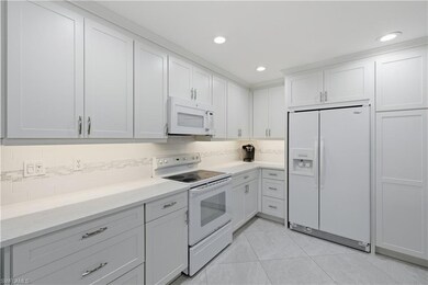 Kitchen featuring white appliances, decorative backsplash, white cabinets, recessed lighting, and light tile patterned flooring
