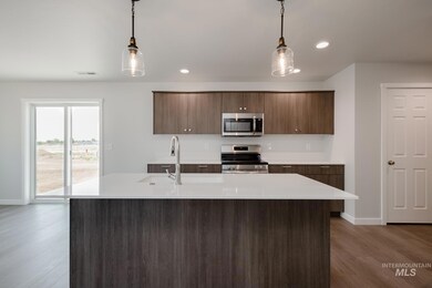Kitchen featuring stainless steel appliances, light countertops, wood finished floors, pendant lighting, and recessed lighting