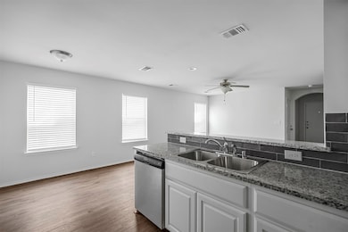 Kitchen with white cabinetry, dishwasher, light stone countertops, dark wood finished floors, and a ceiling fan