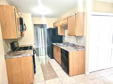 Kitchen with black appliances, decorative backsplash, light tile patterned flooring, and light brown cabinetry