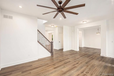 Unfurnished living room featuring stairway, recessed lighting, wood finished floors, and a ceiling fan