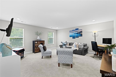 Living room with light carpet, recessed lighting, and a desk