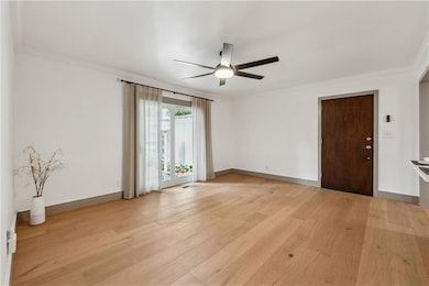 Empty room with ornamental molding, light wood finished floors, and a ceiling fan