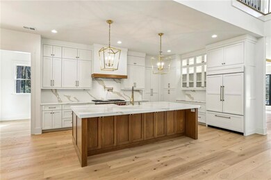 Kitchen with recessed lighting, paneled built in refrigerator, light wood-style floors, white cabinets, and tasteful backsplash