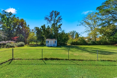 Fenced backyard with a storage shed and view of scattered trees