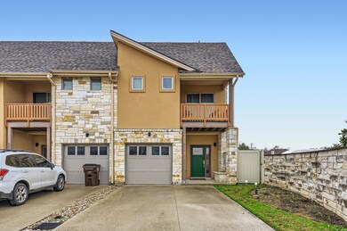 Townhome / multi-family property with stone siding, driveway, stucco siding, and roof with shingles