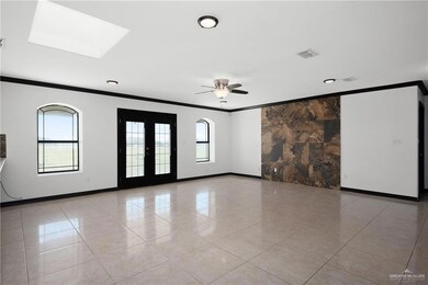 Tiled spare room featuring ceiling fan, crown molding, french doors, and a skylight