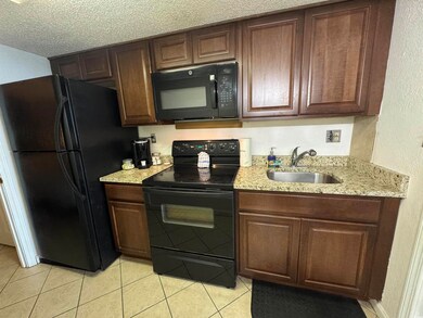 Kitchen with black appliances, a sink, light tile 