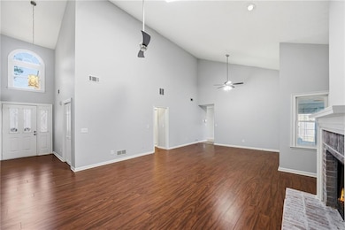 Unfurnished living room with high vaulted ceiling, a fireplace, dark wood-style flooring, and a ceiling fan