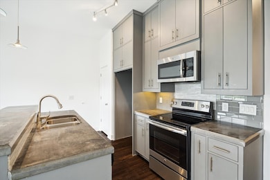 The kitchen features concrete counter tops, range, built in microwave and pantry..