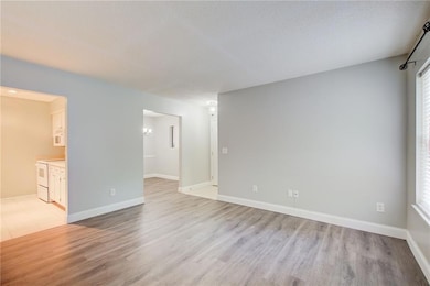 Empty room featuring light wood finished floors, baseboards, and a textured ceiling