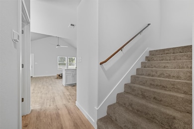 Staircase with wood finished floors, a ceiling fan, and high vaulted ceiling