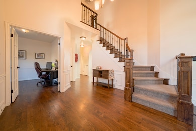 Entrance foyer with dark wood flooring, stairway, and a high ceiling