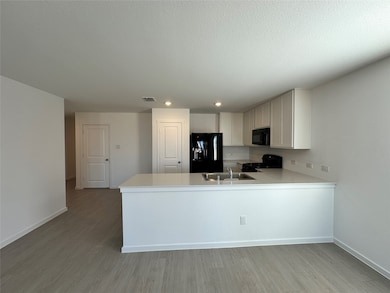 Kitchen with light countertops, black appliances, light wood-style floors, a peninsula, and white cabinetry