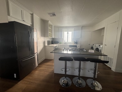 Kitchen with white cabinetry, appliances with stainless steel finishes, a kitchen island, dark wood-type flooring, and a textured ceiling