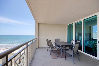 Balcony with view of water and beach and outdoor dining space