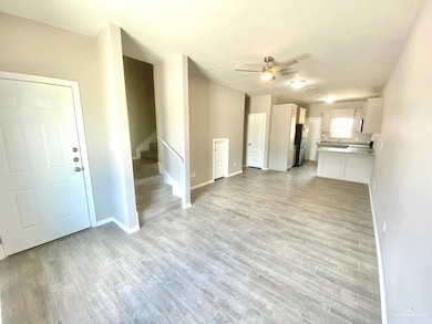 Unfurnished living room featuring stairway, a ceiling fan, and light wood-style flooring