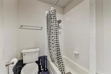 Bathroom featuring a textured ceiling, toilet, and