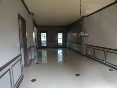 Spare room featuring crown molding, a decorative wall, wainscoting, and tile patterned floors
