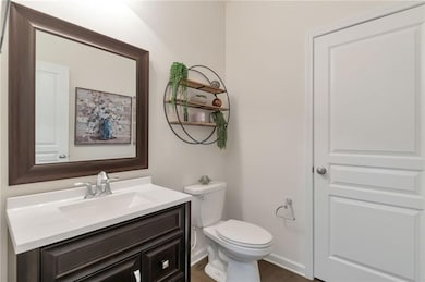 Half bath featuring baseboards, wood finished floors, toilet, and vanity
