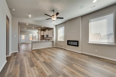 Unfurnished living room featuring ceiling fan, recessed lighting, light wood finished floors, and a glass covered fireplace