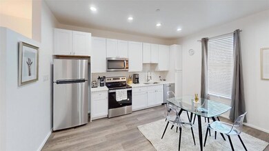 Kitchen with white cabinetry, sink, light wood-typ